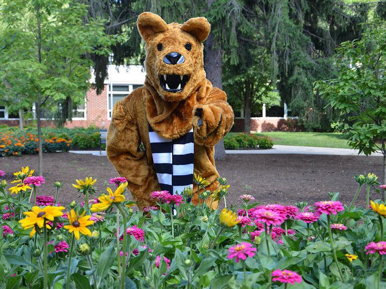 The Nittany Lion posing behind a clump of flowers